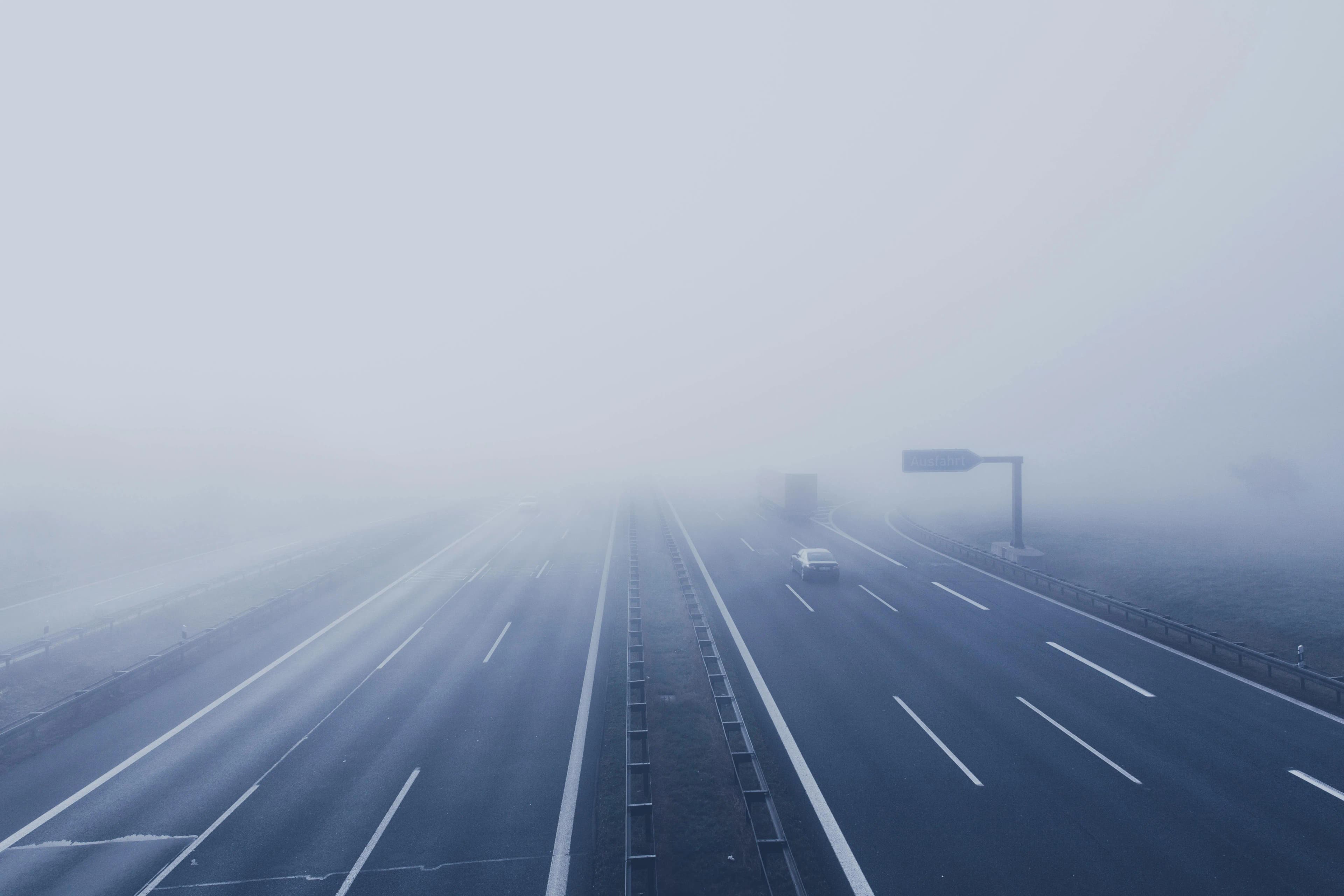 Foggy highway with lanes disappearing into low visibility