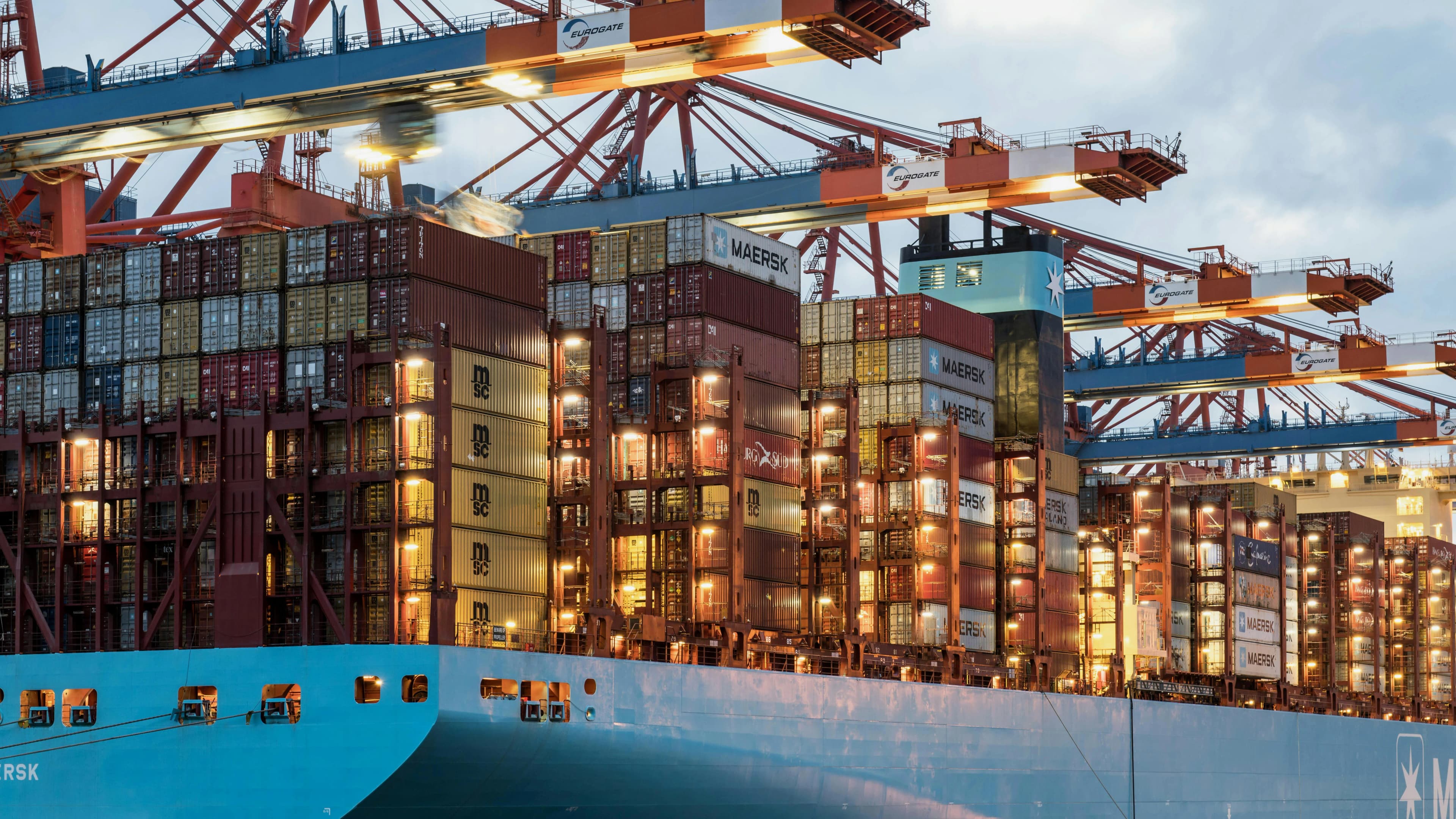 Container ship under port cranes at night