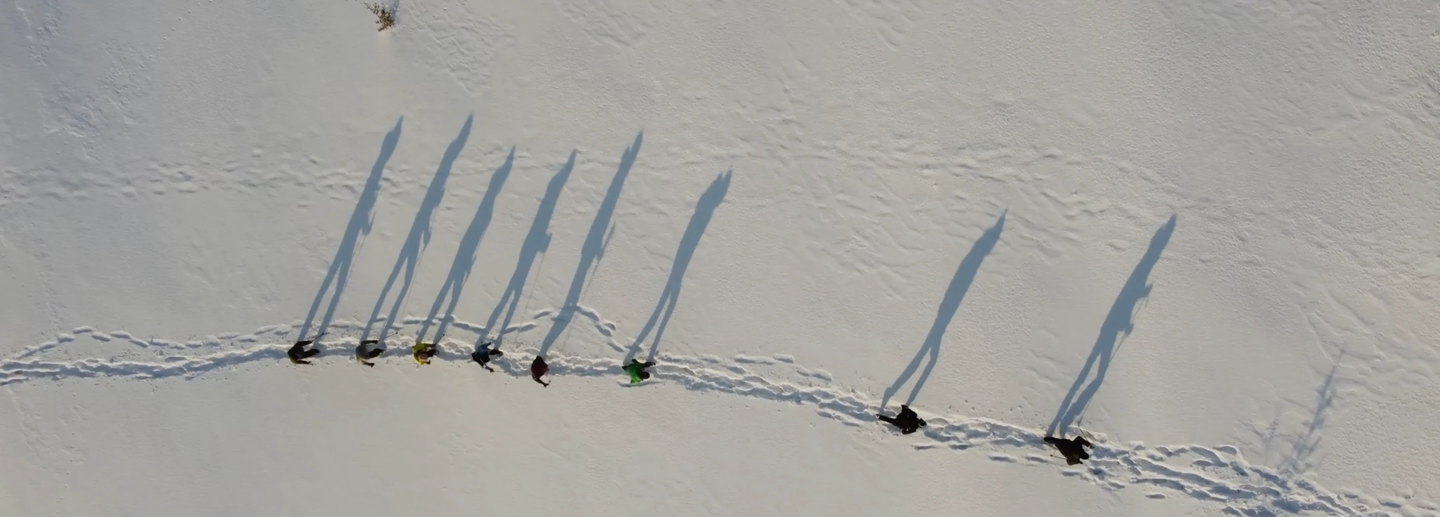 Luftaufnahme einer Gruppe, die in einer Spur durch den Schnee geht